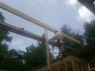 Carpenter setting a ridge beam over a new addition frame — Ice Dam Removal by Roofing Brothers in Point Lookout