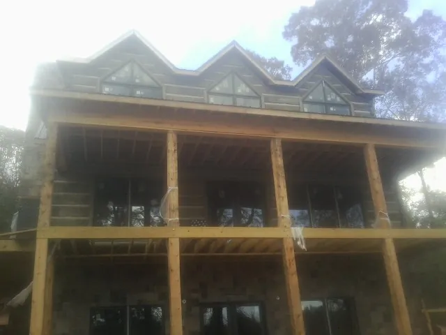 Dormers and porch framing on a large log home under construction — Roof Coating work by our crew in Point Lookout