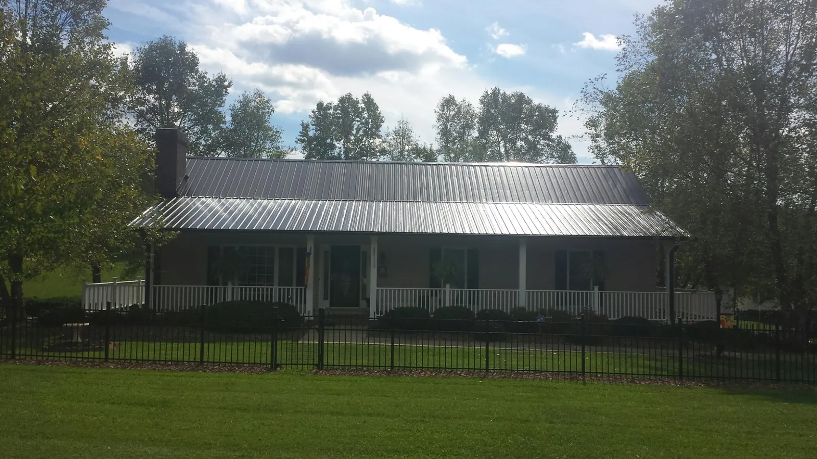 Gray metal roof on a brick ranch with a full width front porch — Gutter Guard Installation work by our crew in Point Lookout