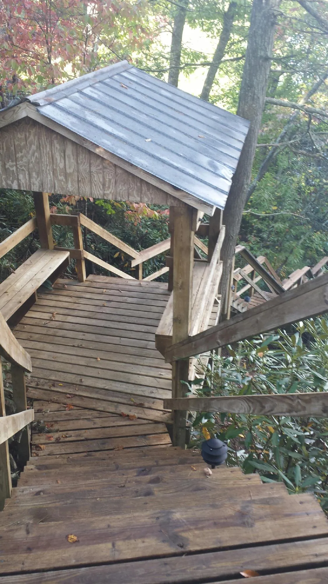 Metal roofed shelter over wooden steps on a wooded walkway — Skylight Repair & Installation work by our crew in Point Lookout
