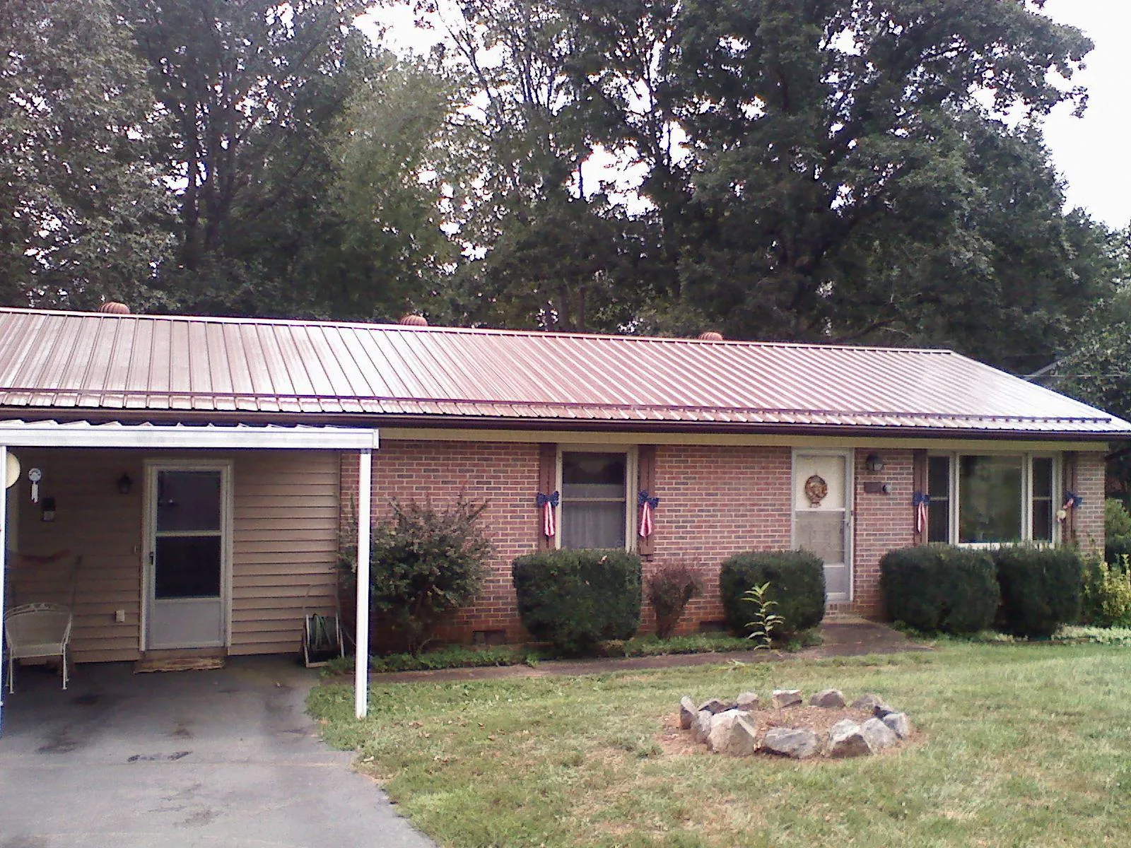 Bronze metal roof and carport on a brick ranch home — Roof Repair work by our crew in Point Lookout