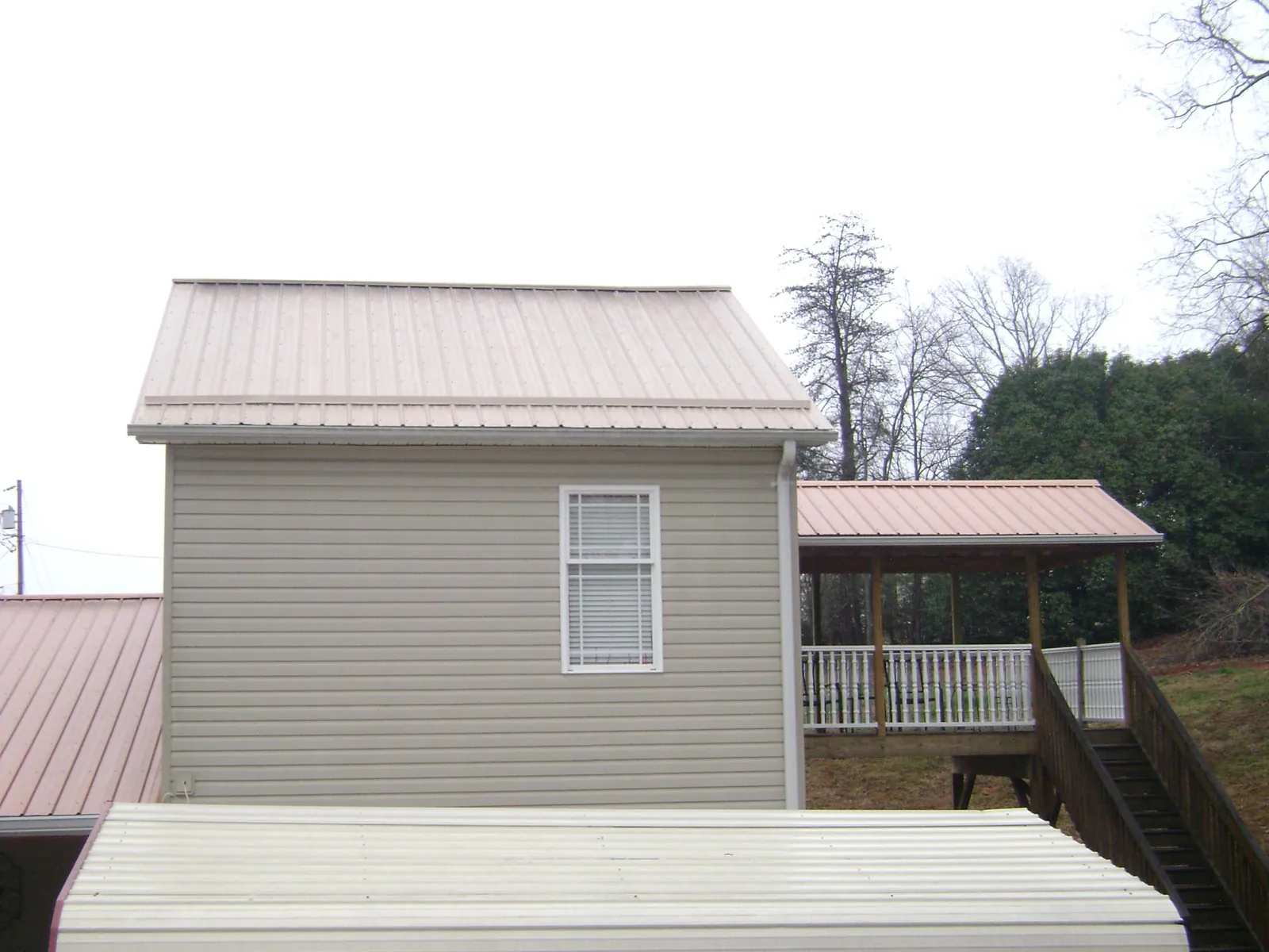 Tan metal roofs on a two story addition and attached porch, from a Roof Replacement job in Point Lookout