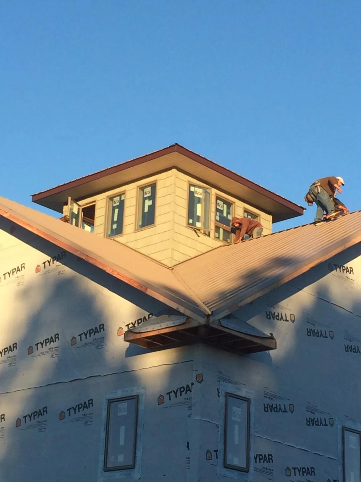 Roofers working around a rooftop cupola on a new metal roof at sunset — Roof Waterproofing in Point Lookout by Roofing Brothers